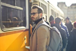 Man in Brown Coat and Gray Backpack Posing for a Photo